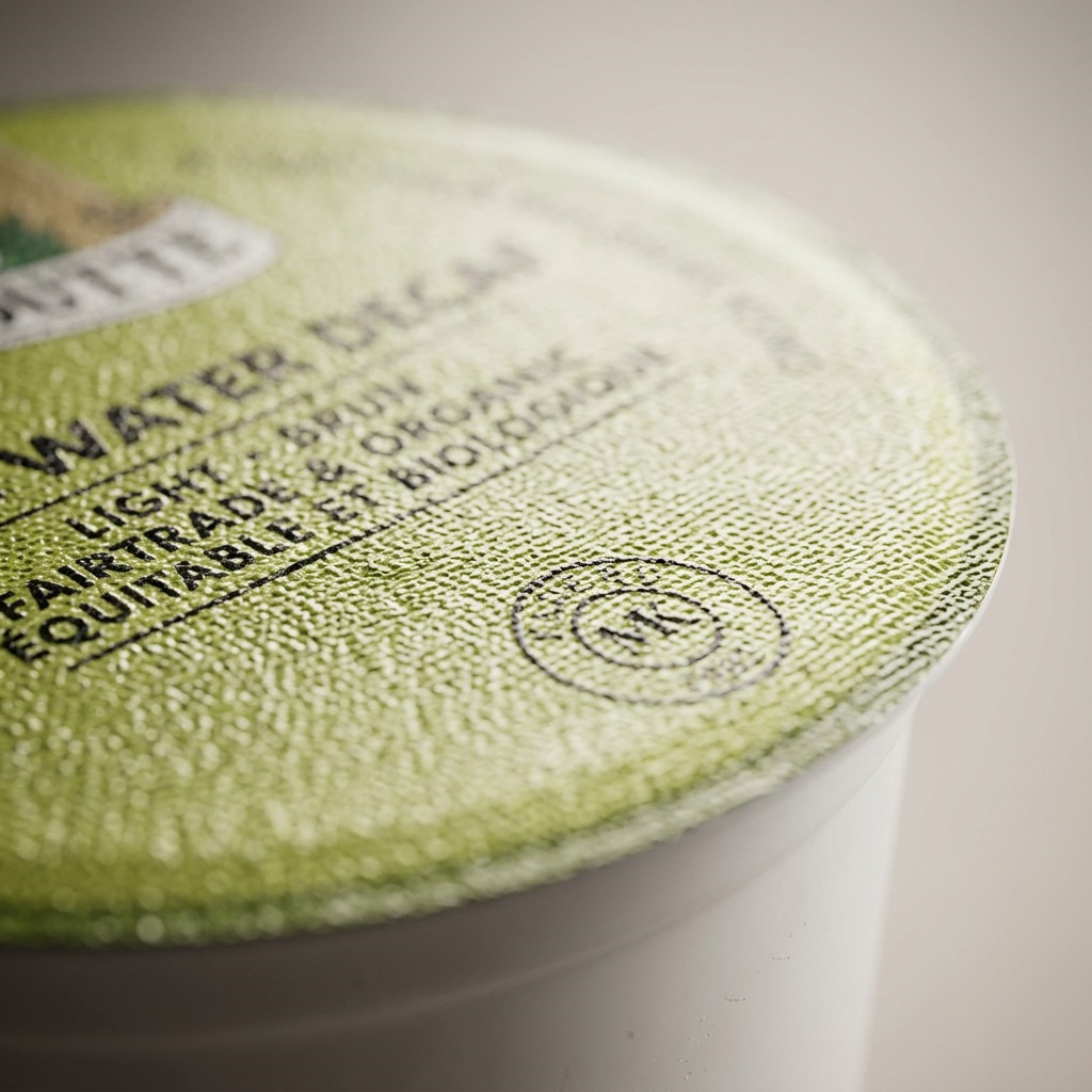 Macro photograph of the Van Houtte single serve K-Cup lid, focusing on the texture of the foil and the detail of the printed text.