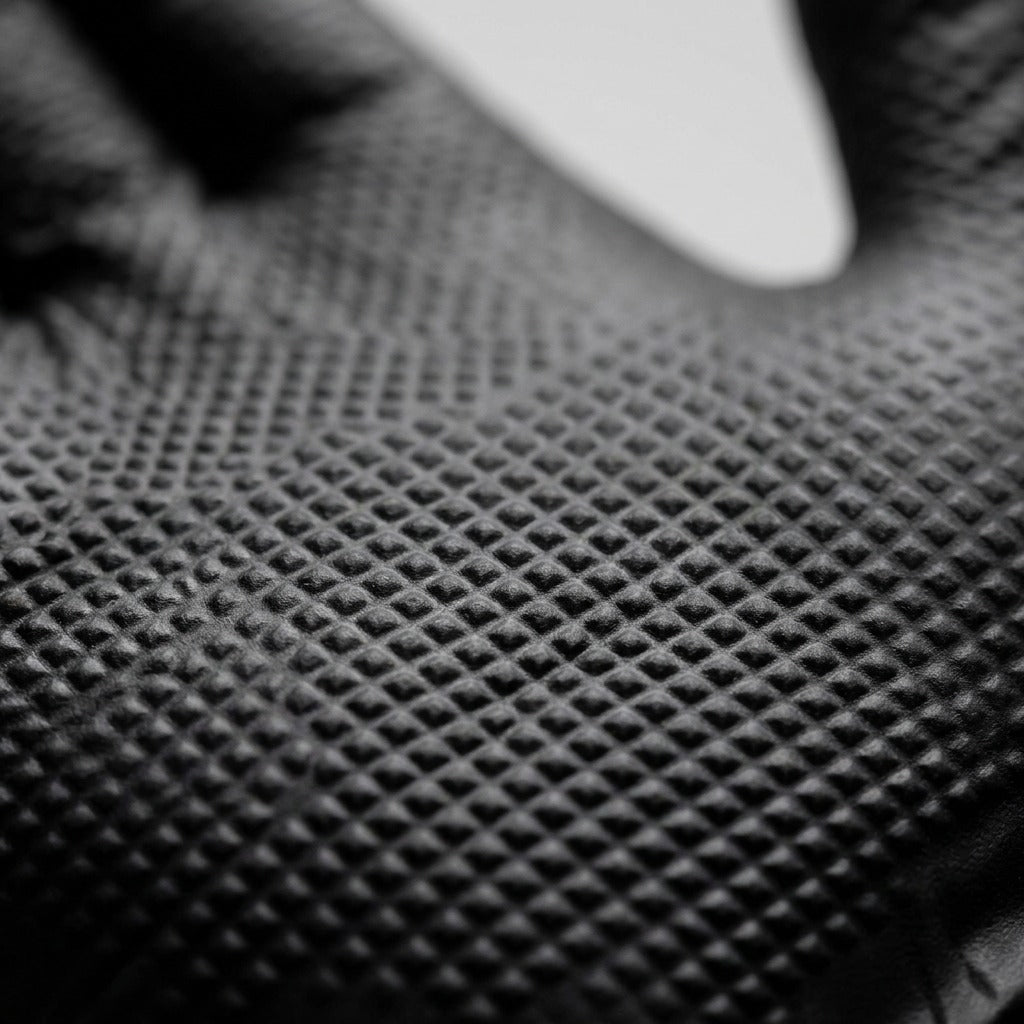 Macro detail of the raised diamond grip texture on a Globe black 8mil nitrile glove.