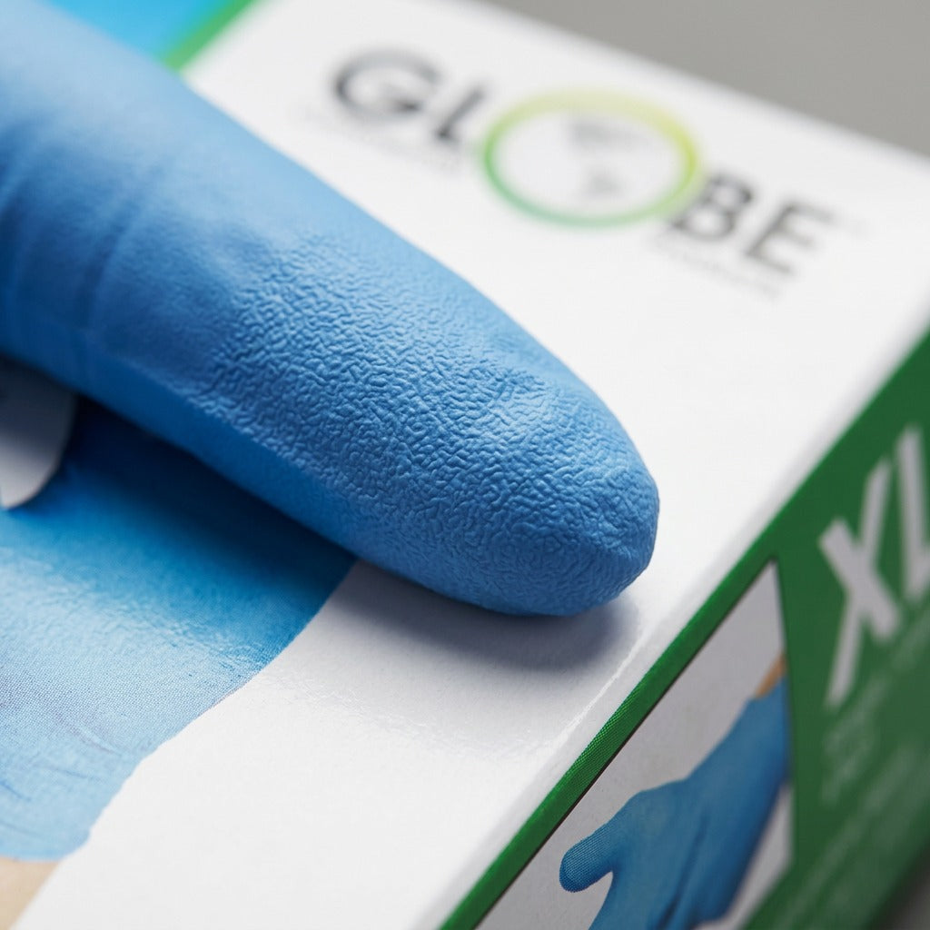Macro detail of a sky blue Globe nitrile glove fingertip showing the textured grip and 4mil thickness.