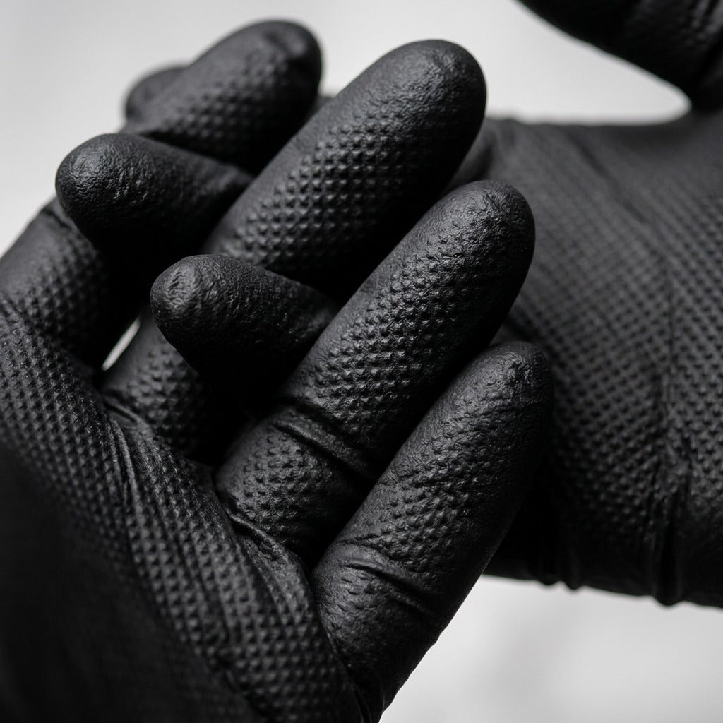 Macro detail of black Globe Precision Grip nitrile gloves showing the heavy-duty diamond texture.