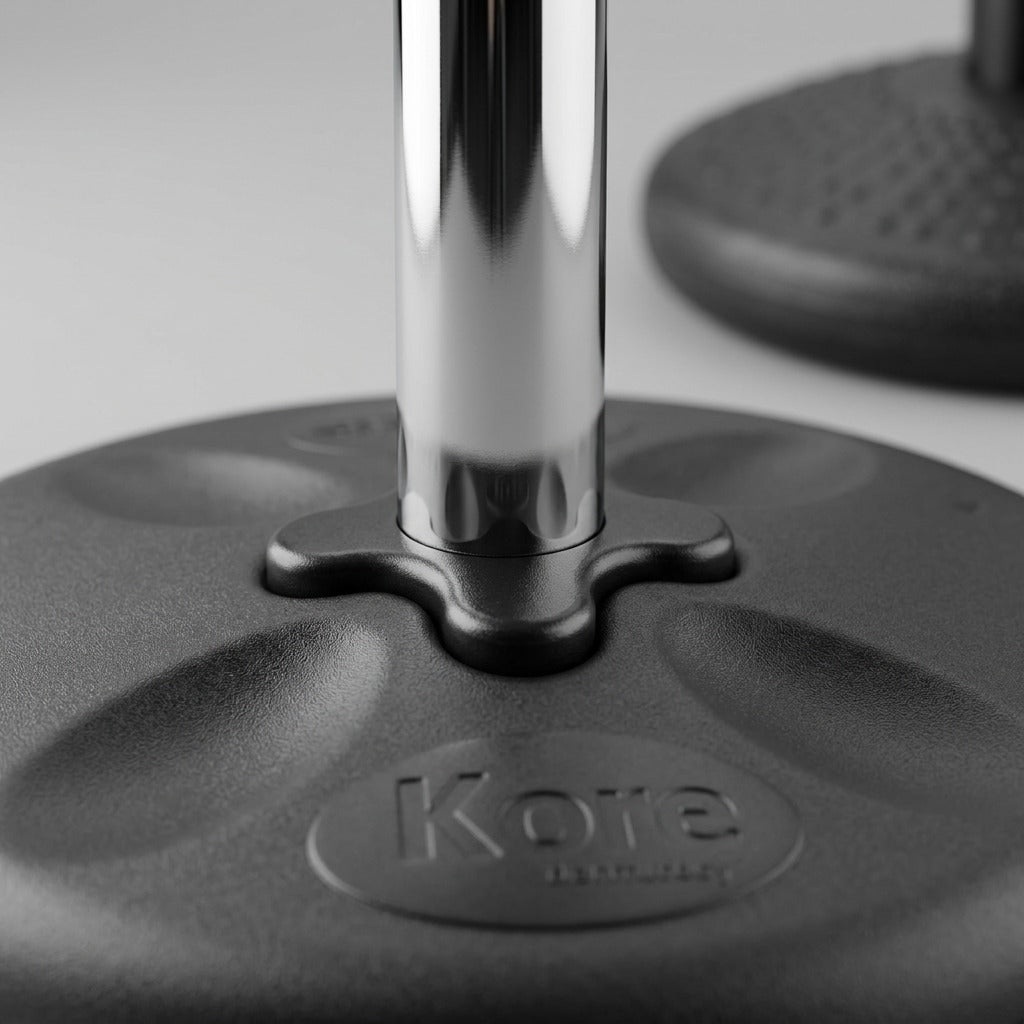 Macro detail of the Kore Adjustable Wobble Stool's chrome pedestal and textured black base.